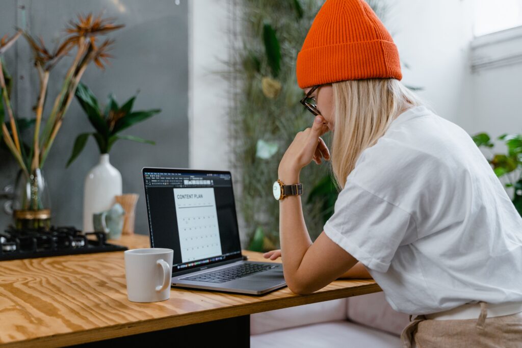 Woman in an orange hat looking at a laptop thinking about tax return checklists