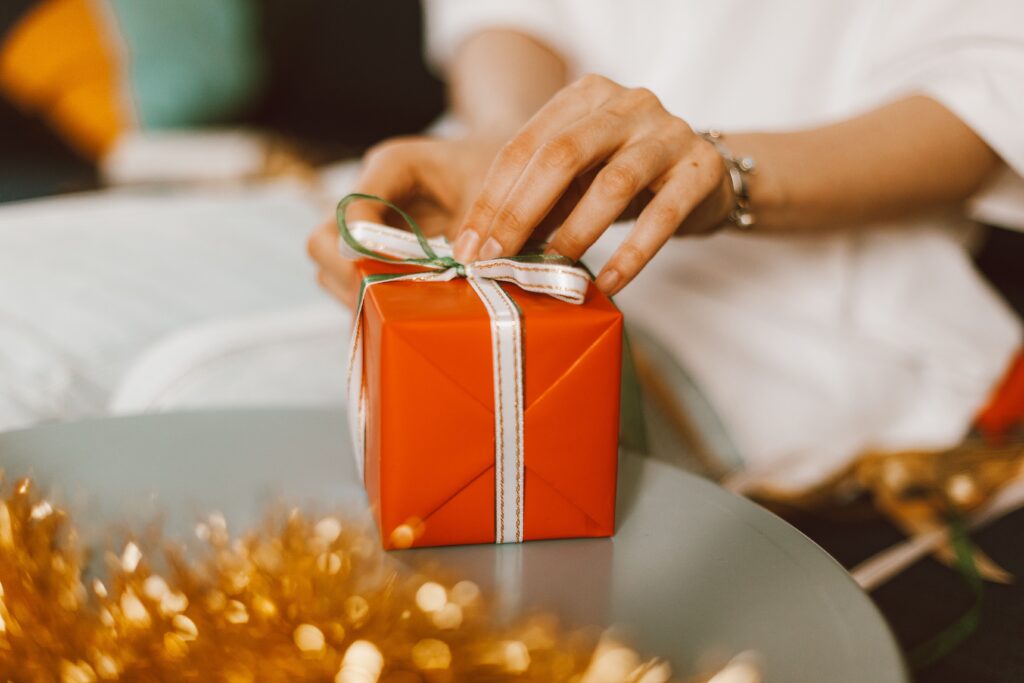 Person holding an orange wrapped Christmas present